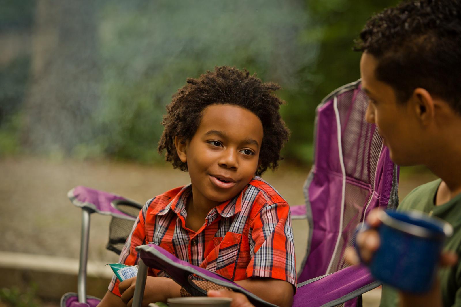Young boy sits in front of a campfire at Sloppy Floyd